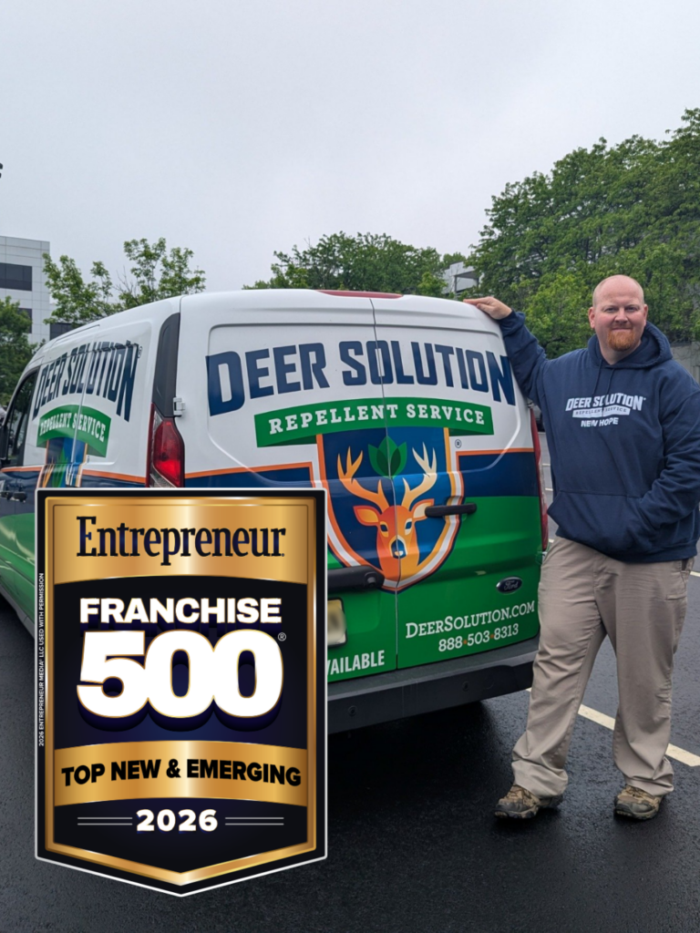 A Deer Solution franchise owner standing with a branded service van, featuring the Entrepreneur Franchise 500 Top New & Emerging 2026 award logo.